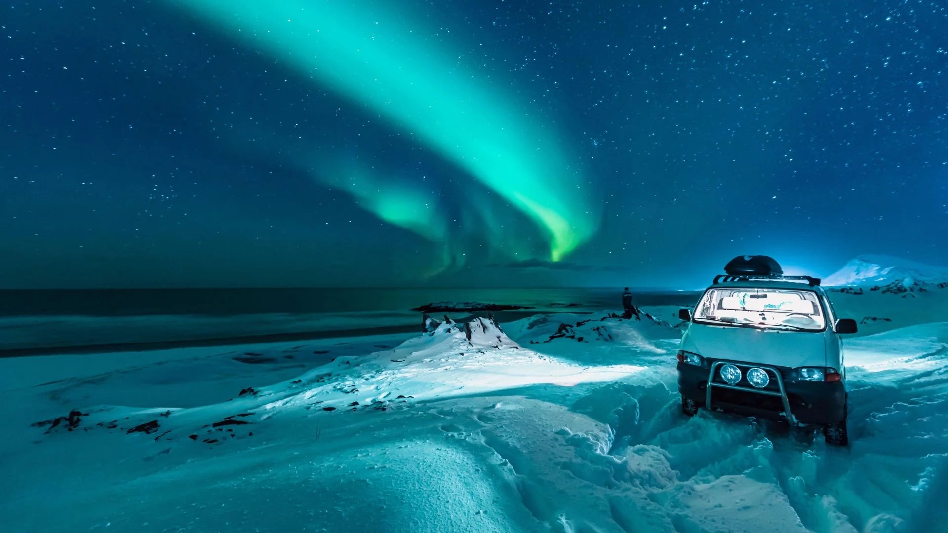 Car under the Northern Lights in a snowy landscape